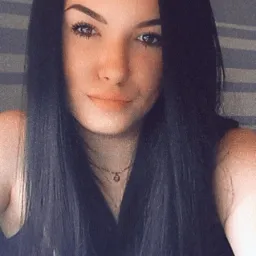 Portret młodej kobiety z długimi, czarnymi włosami, delikatnym makijażem i subtelną biżuterią na szyi.