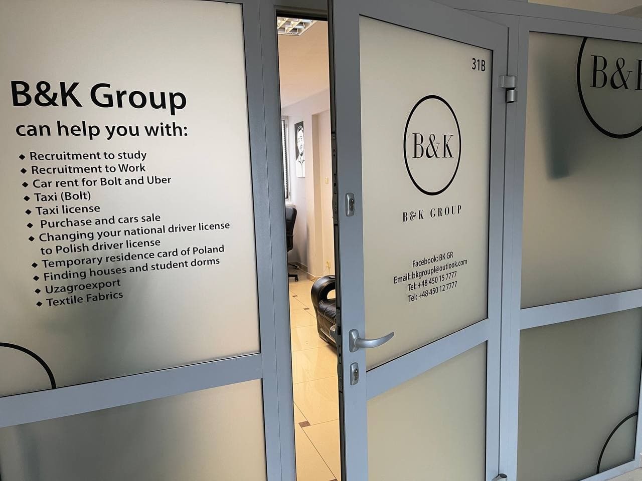 Szklane drzwi wejściowe do biura B&K Group z logo i listą oferowanych usług, w tym rekrutacji, wynajmu aut, licencji taxi i tkanin.