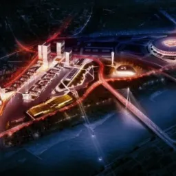 Nocna wizualizacja urbanistyczna z lotu ptaka: kompleks budynków, stadion, most i rzeka, oświetlone czerwonymi liniami komunikacyjnymi.