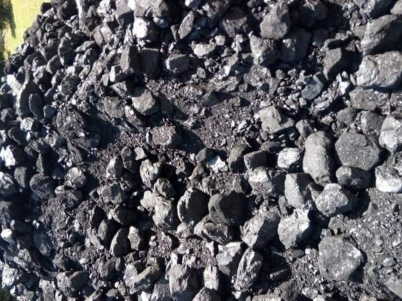 Góra czarnego węgla kamiennego, widoczne różne frakcje, od drobnego miału po większe bryły, oświetlone naturalnym światłem.