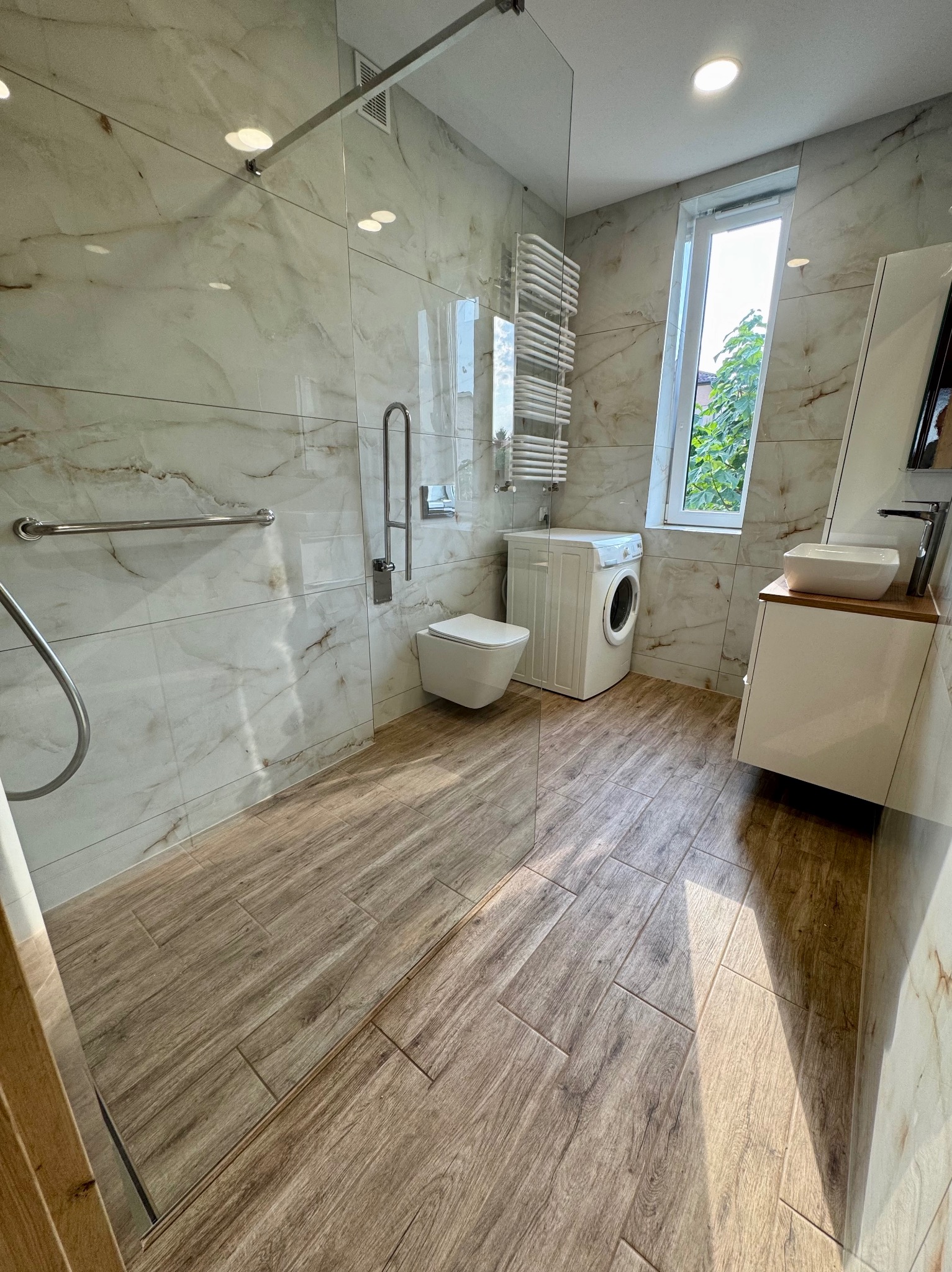 Jasne płytki wielkoformatowe i drewnopodobna podłoga – świeży design łazienki