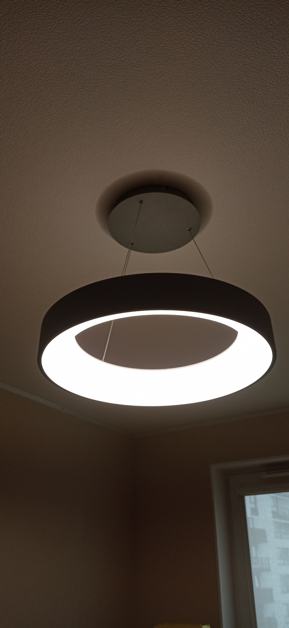 Nowoczesna okrągła lampa LED wisząca, zamontowana na suficie, oświetlająca pomieszczenie, widok z dołu.