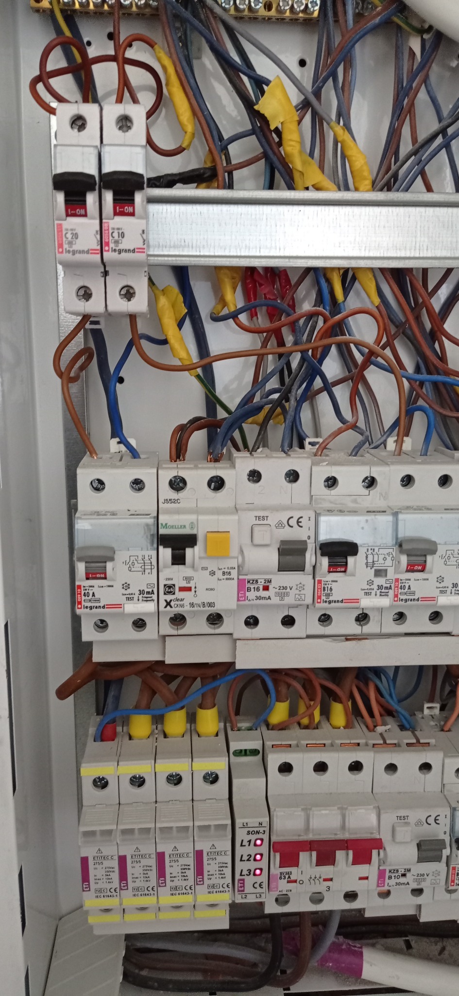 Rozdzielnica elektryczna z bezpiecznikami różnych typów (Legrand, Moeller, Etitec) i okablowaniem, widok z bliska, Warszawa.