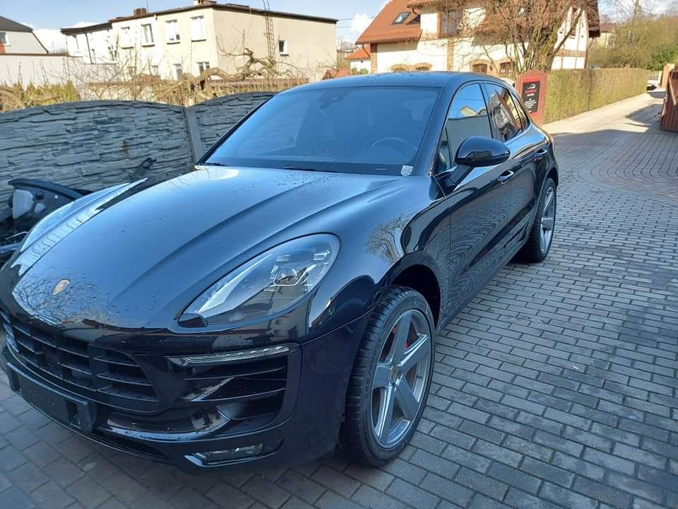 Czarny Porsche Macan po umyciu, stojący na brukowanym podjeździe; widoczne krople wody na karoserii i felgi z czerwonymi zaciskami hamulcowymi.