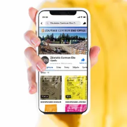 Osoba trzyma telefon z wyświetlonym profilem firmy Zduńskie Centrum Eko Opału na Facebooku, prezentującym ofertę ekogroszku w workach 20 kg.