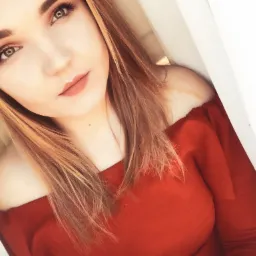 Portret kobiety z długimi blond włosami, w czerwonej bluzce z odkrytymi ramionami, patrzącej w górę.