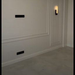 EDE GROUP SPÓŁKA Z OGRANICZONĄ ODPOWIEDZIALNOŚCIĄ - Eleganckie wykończenie wnętrza: białe ściany z dekoracyjnymi listwami, nowoczesne oświetlenie sufitowe i ścienne, minimalistyczne gniazdka. Subtelny design.