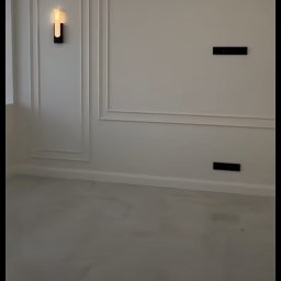 EDE GROUP SPÓŁKA Z OGRANICZONĄ ODPOWIEDZIALNOŚCIĄ - Eleganckie wykończenie wnętrza: białe ściany z dekoracyjnymi listwami, nowoczesne oświetlenie sufitowe i ścienne. Minimalistyczny design, jasne kolory.