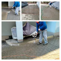 Czyszczenie kostki brukowej myjką ciśnieniową, widoczne różnice w czystości, osłonięty motocykl w tle, zielony wąż i pomarańczowy kabel na kostce.