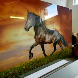 Duży szklany panel z nadrukiem biegnącego konia na tle zachodzącego słońca, widoczne mocowanie do ściany, w tle okno i lampa