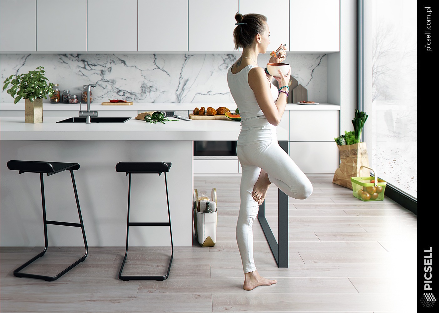 Nowoczesna, minimalistyczna kuchnia w bieli z marmurowym backsplash'em; kobieta w białym stroju je posiłek, stojąc na jednej nodze przy wyspie kuchennej, na blacie warzywa i owoce.