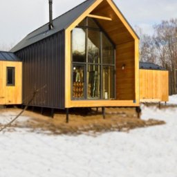 Solenwood Sp. z o. o - Nowoczesny dom z drewnianą elewacją i dużym przeszkleniem, posadowiony na słupach, otoczony śnieżnym krajobrazem.