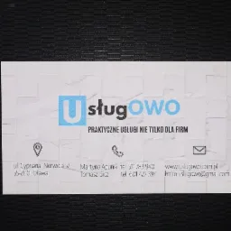 Wizytówka firmy Usługowo z adresem, numerami telefonów i adresem email, na ciemnym tle.