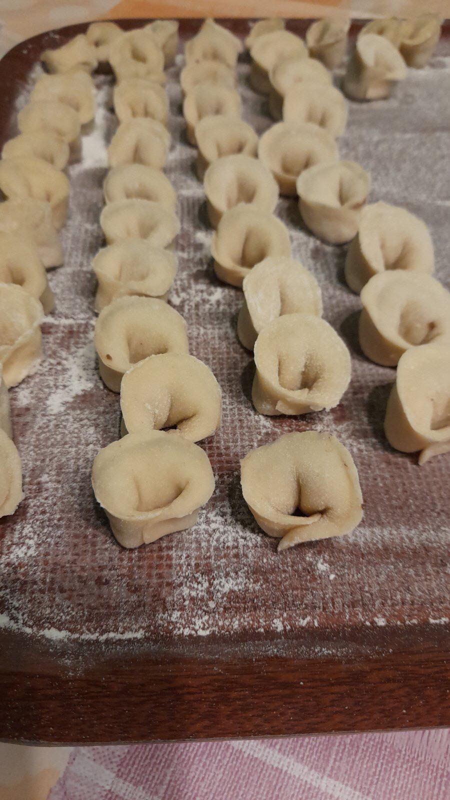 Ręcznie lepione pierogi na drewnianej tacy posypanej mąką, przygotowywane w Gliwicach.