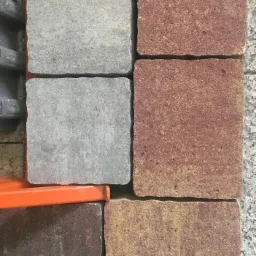 Przykładowe ułożenie kostki brukowej: szare i czerwono-brązowe elementy na palecie transportowej, widoczne detale faktury i kolorystyki.