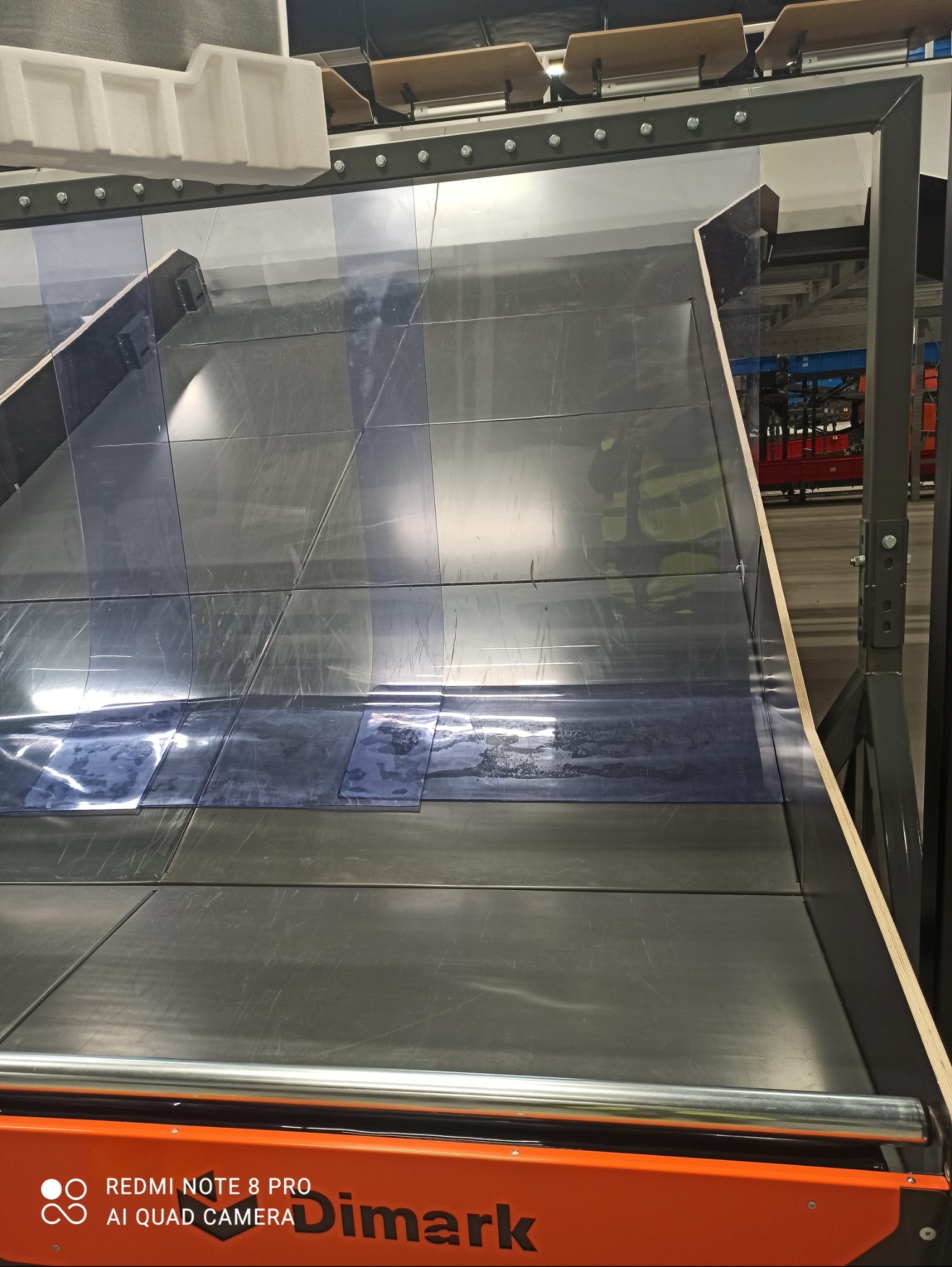 Przemysłowa linia produkcyjna z panelami, prawdopodobnie do obróbki lub czyszczenia, widoczne ślady użytkowania na powierzchni paneli.