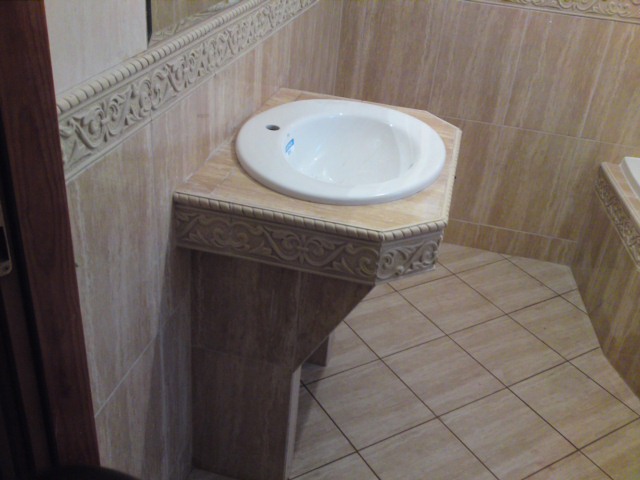 Umywalka z dekoracyjnym postumentem i beżowymi płytkami w łazience w Legionowie. Widoczna również listwa dekoracyjna na ścianie.