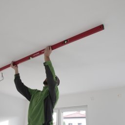 Sprawdzanie stropu i sufitu przy pomocy łaty budowlanej z poziomnicą.
