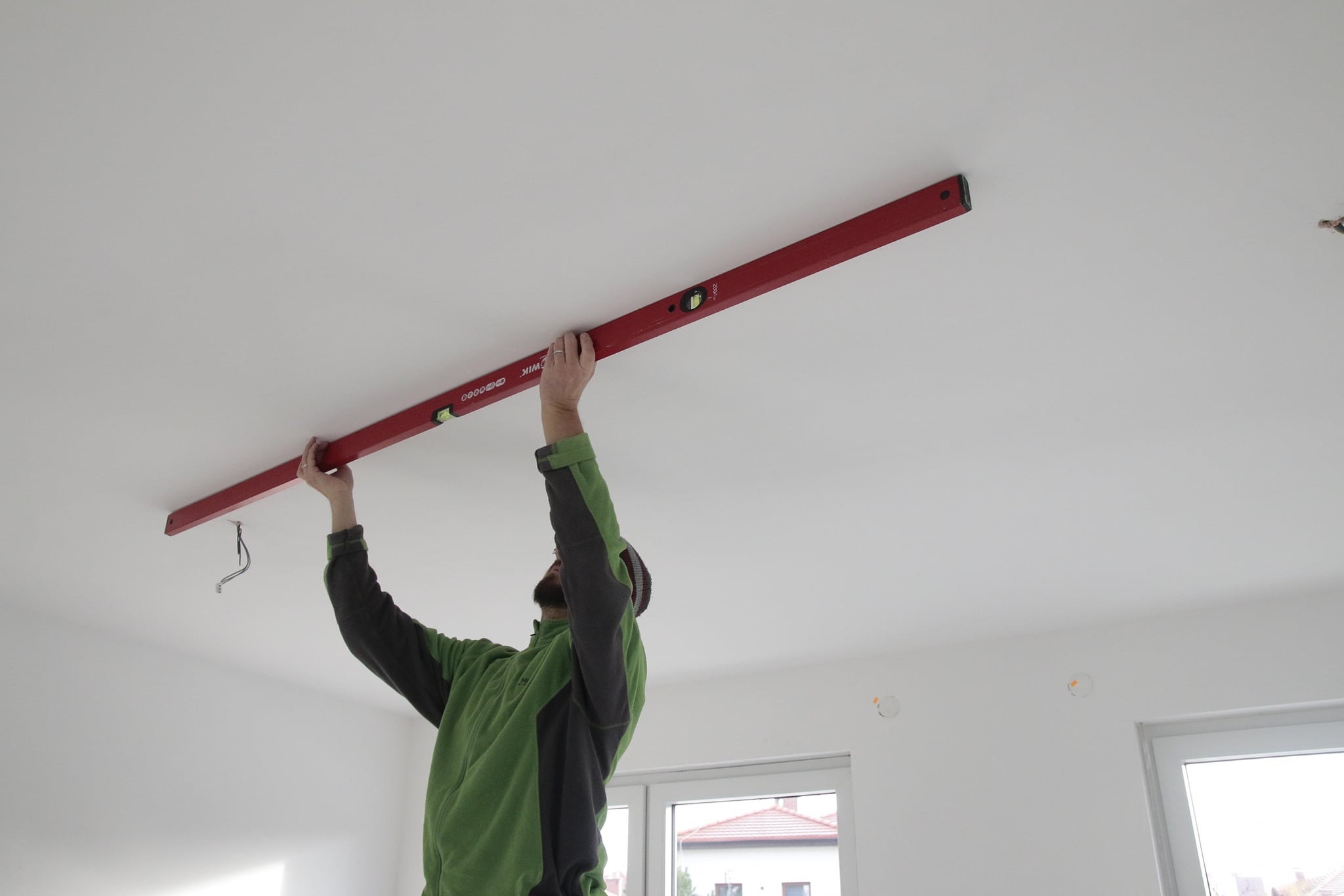 Sprawdzanie stropu i sufitu przy pomocy łaty budowlanej z poziomnicą.