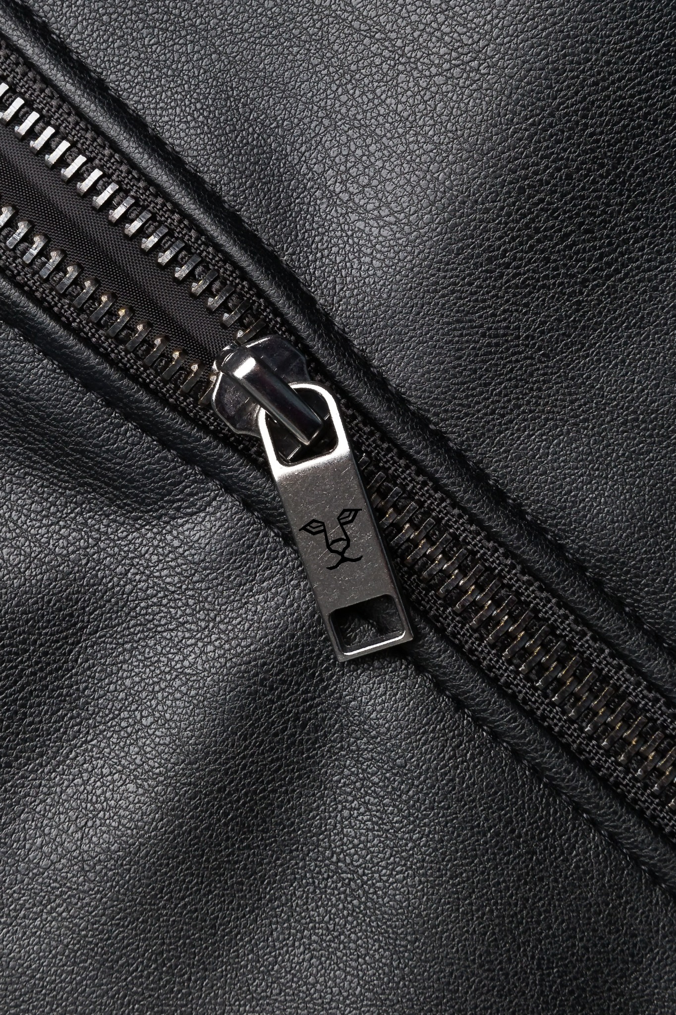 Czarna skórzana kurtka z metalowym zamkiem błyskawicznym, na suwaku wygrawerowana głowa lwa.