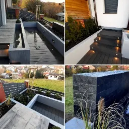 Nowoczesny ogród z elementami wodnymi, drewnianym tarasem, oświetleniem LED w schodach i geometrycznymi rabatami z czarnym kamieniem, widok z góry na okoliczne domy.