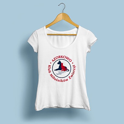 Biała koszulka damska z okrągłym nadrukiem: sylwetka psa i kota w okręgu z napisem 'AZORKOWO Klub Miłośników Zwierząt', wisząca na drewnianym wieszaku na tle błękitnej ściany.