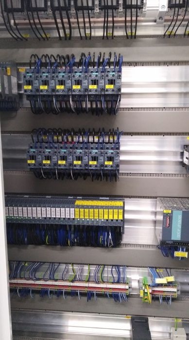 Wnętrze szafy sterowniczej z modułami Siemens, licznymi przewodami i listwami zaciskowymi, widoczne okablowanie i elementy automatyki przemysłowej.