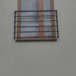 Metalowa balustrada okienna z poziomymi prętami, zamontowana na elewacji budynku z drewnianą ramą okienną, widok z dołu na tle drabiny.