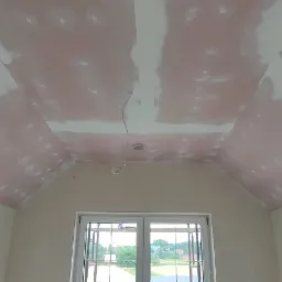 Skośny sufit poddasza w Schlangenbad po nałożeniu pierwszej warstwy gładzi, widoczne łączenia płyt kartonowo-gipsowych i przygotowanie do dalszych prac wykończeniowych.