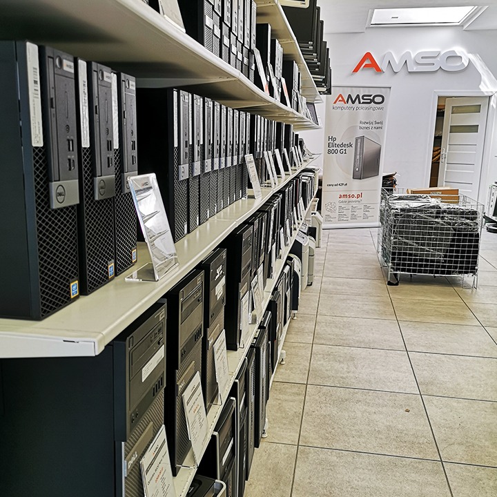 Rząd używanych komputerów stacjonarnych Dell i HP na półkach w sklepie, z etykietami cenowymi, pod szyldem firmy AMSO komputery poleasingowe.