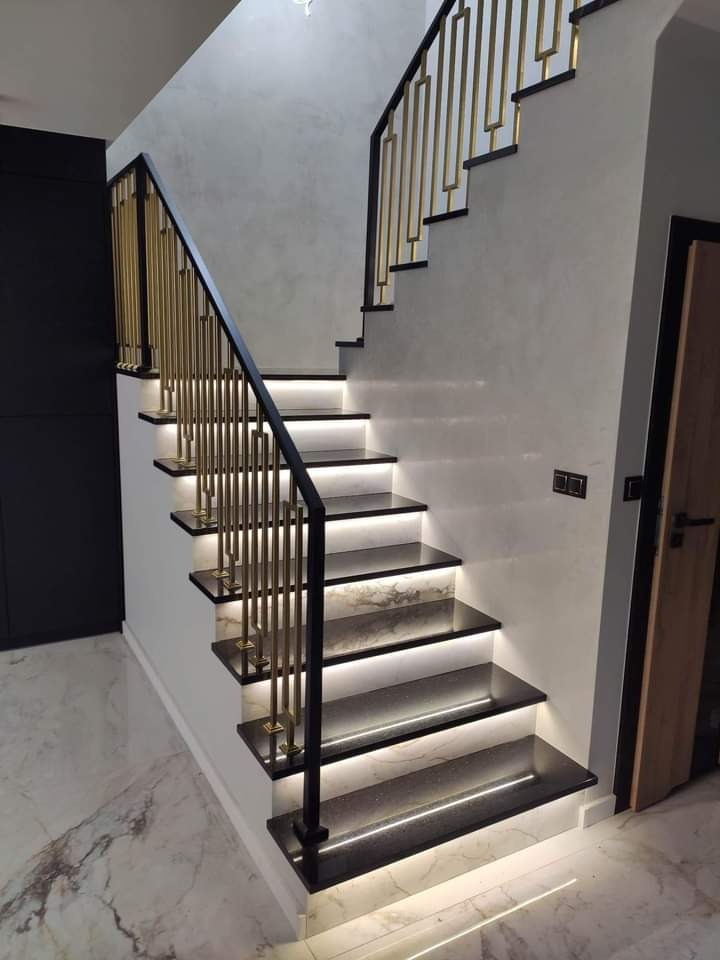 Nowoczesne schody z czarnego kamienia z podświetleniem LED, balustrada w kolorze złota, marmurowa podłoga.