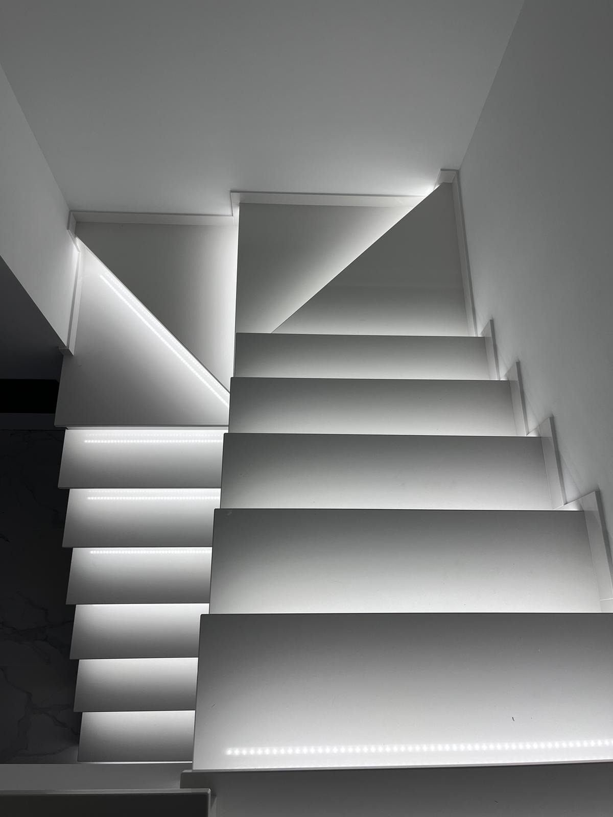 Nowoczesne, białe schody z subtelnym oświetleniem LED w Lubartowie, widok od dołu.