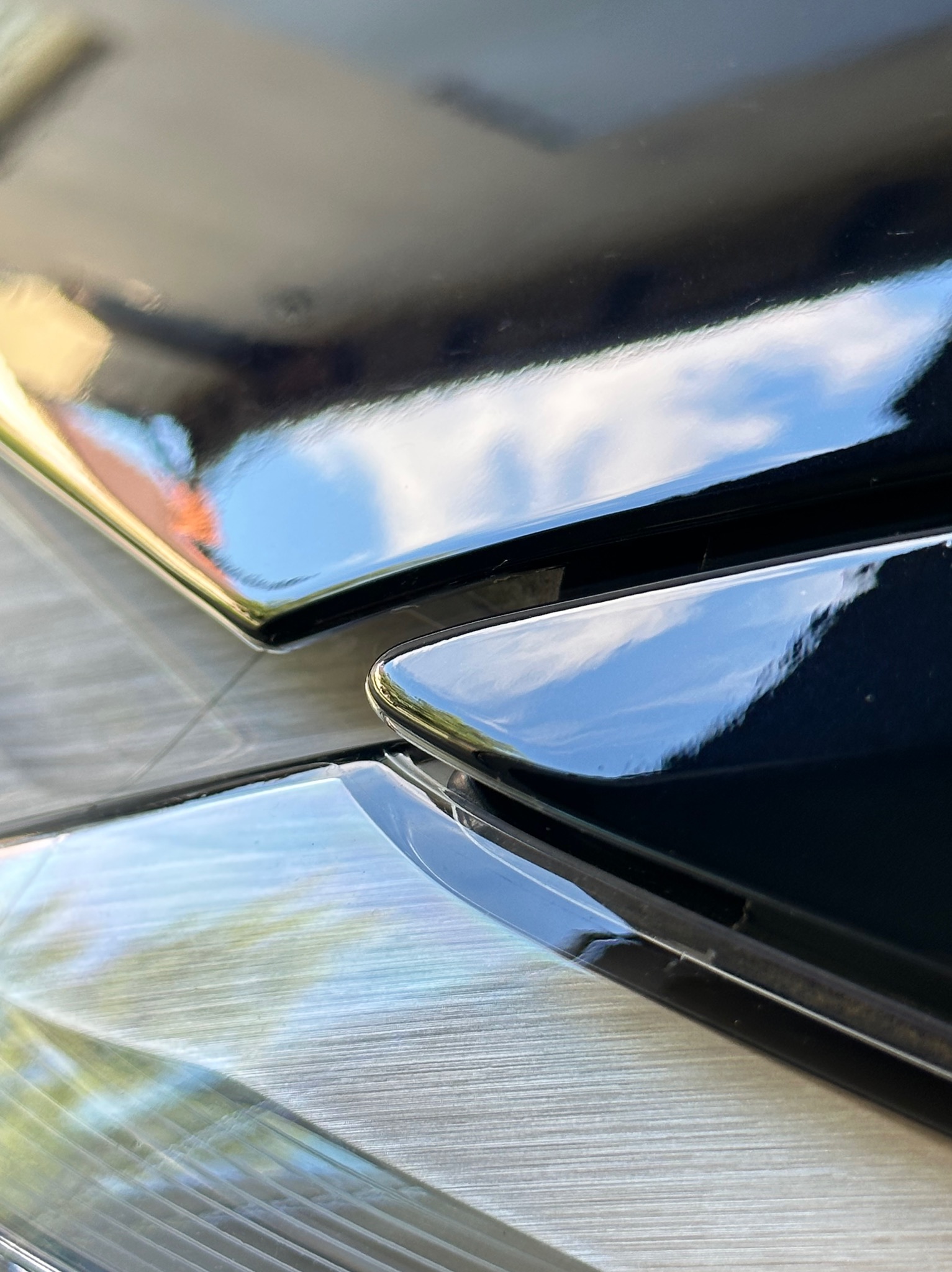 Błyszczące, czarne elementy pieca gazowego z widocznymi refleksami światła i nieba, ułożone na metalowej powierzchni.