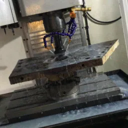 Obróbka CNC metalowego elementu z użyciem chłodziwa, widoczny detal mocowania i dysze chłodziwa.