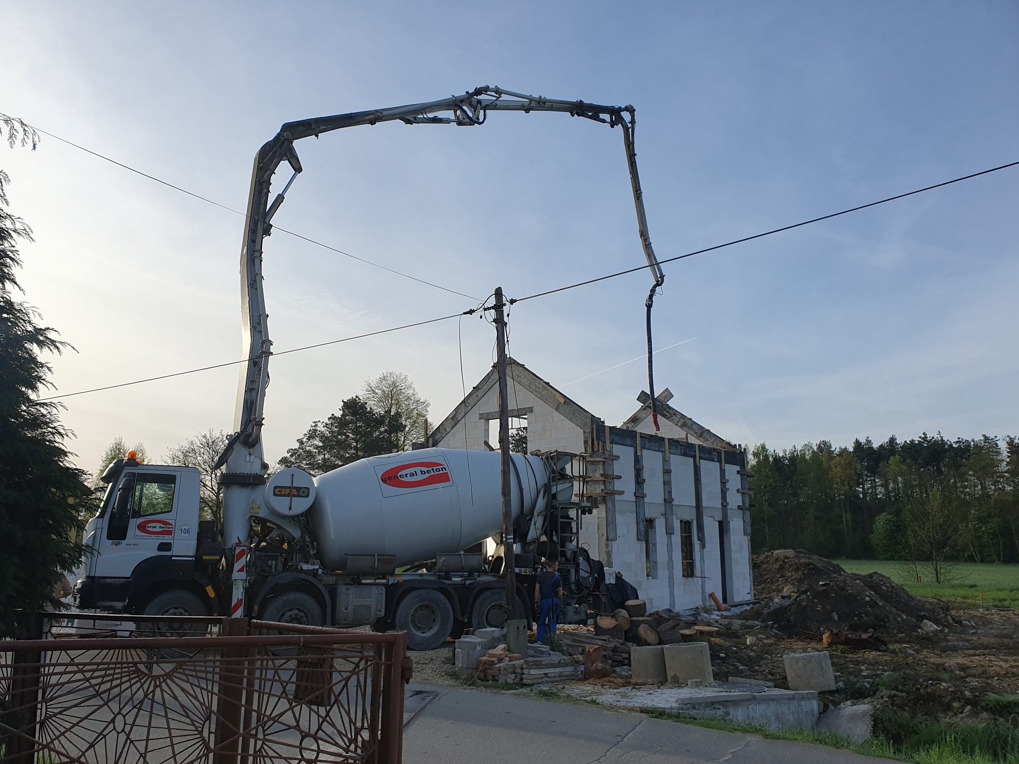 Betonomieszarka z pompą podaje beton do wylewania fundamentów domu w trakcie budowy, widoczna konstrukcja z bloczków i szalunki.