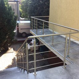 Global Stal Patryk Sidełko - Zewnętrzne schody z poręczą ze stali nierdzewnej w Katowicach, prowadzące do podwyższonego wejścia z balustradą, widoczny fragment białego samochodu dostawczego w tle.
