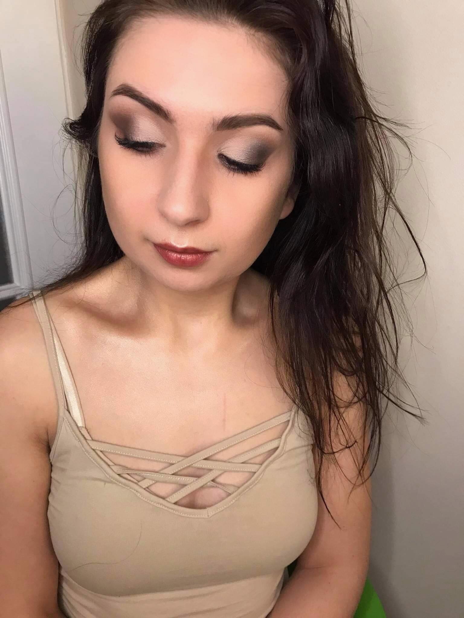 Portret kobiety z zamkniętymi oczami, prezentujący brązowy cień do powiek i błyszczące usta w odcieniu czerwonego wina.