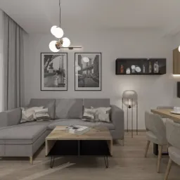 Wnętrze mieszkania w neutralnej kolorystyce: szary narożnik z poduszkami, drewniany stolik kawowy z czarnymi wnękami, czarno-białe grafiki na ścianie, nowoczesne lampy wiszące, drewniany stół...