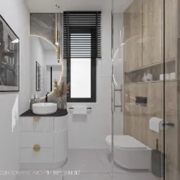 Nowoczesna łazienka z okrągłym lustrem z podświetleniem LED, białą umywalką nablatową na szafce z frezowanymi frontami, drewnianymi szafkami wiszącymi i szarą ścianą z półkami na kosmetyki.