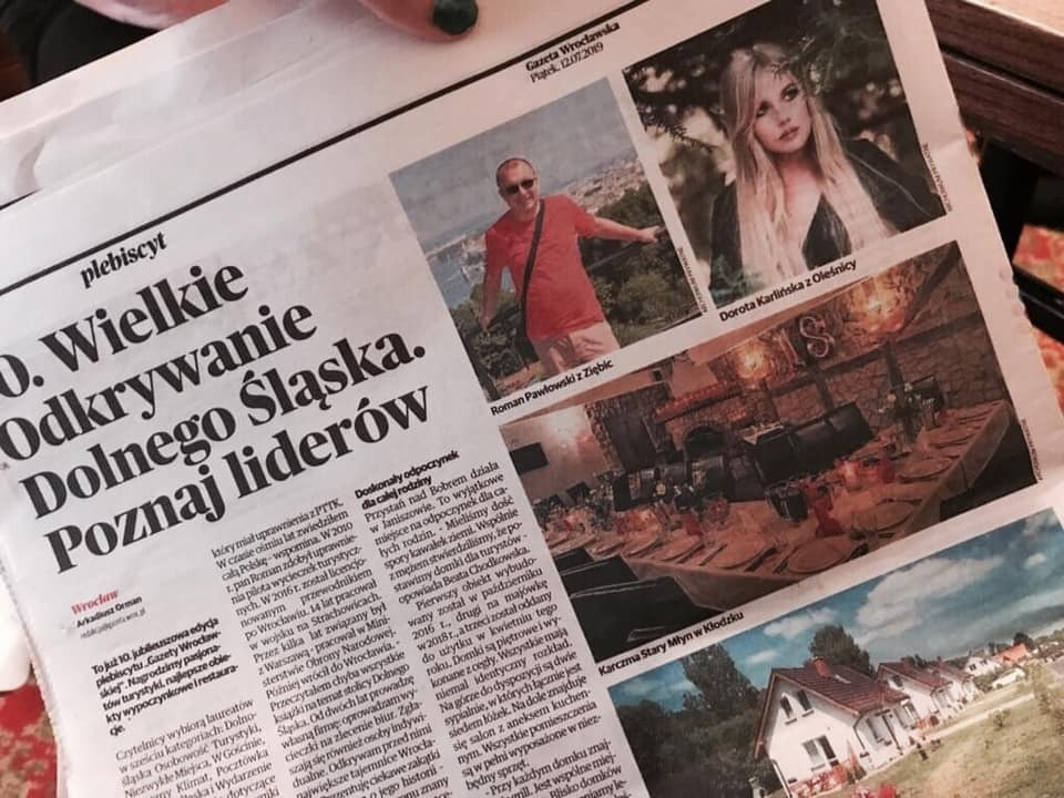 Zdjęcie gazety z artykułem o odkrywaniu Dolnego Śląska, z fotografiami osób i miejsc, w tym wnętrza restauracji i domków letniskowych.