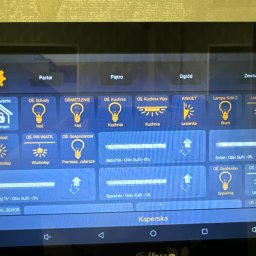Connect Home Paweł Suchoń - Ekran tabletu z interfejsem systemu zarządzania oświetleniem w domu, widoczne ikony i nazwy pomieszczeń: parter, piętro, ogród, hol, kuchnia, łazienka, biuro, sypialnia, wiatrołap, jadalnia, salon,...