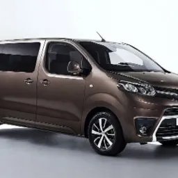 Brązowy van Toyota Proace Verso z ciemnymi szybami, prezentowany na jasnym tle studyjnym.