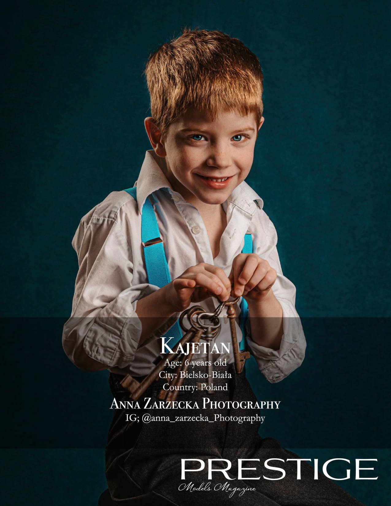 Uśmiechnięty sześcioletni chłopiec z rudymi włosami i niebieskimi oczami, ubrany w białą koszulę i niebieskie szelki, trzymający w dłoniach pęk starych kluczy na ciemnym tle.