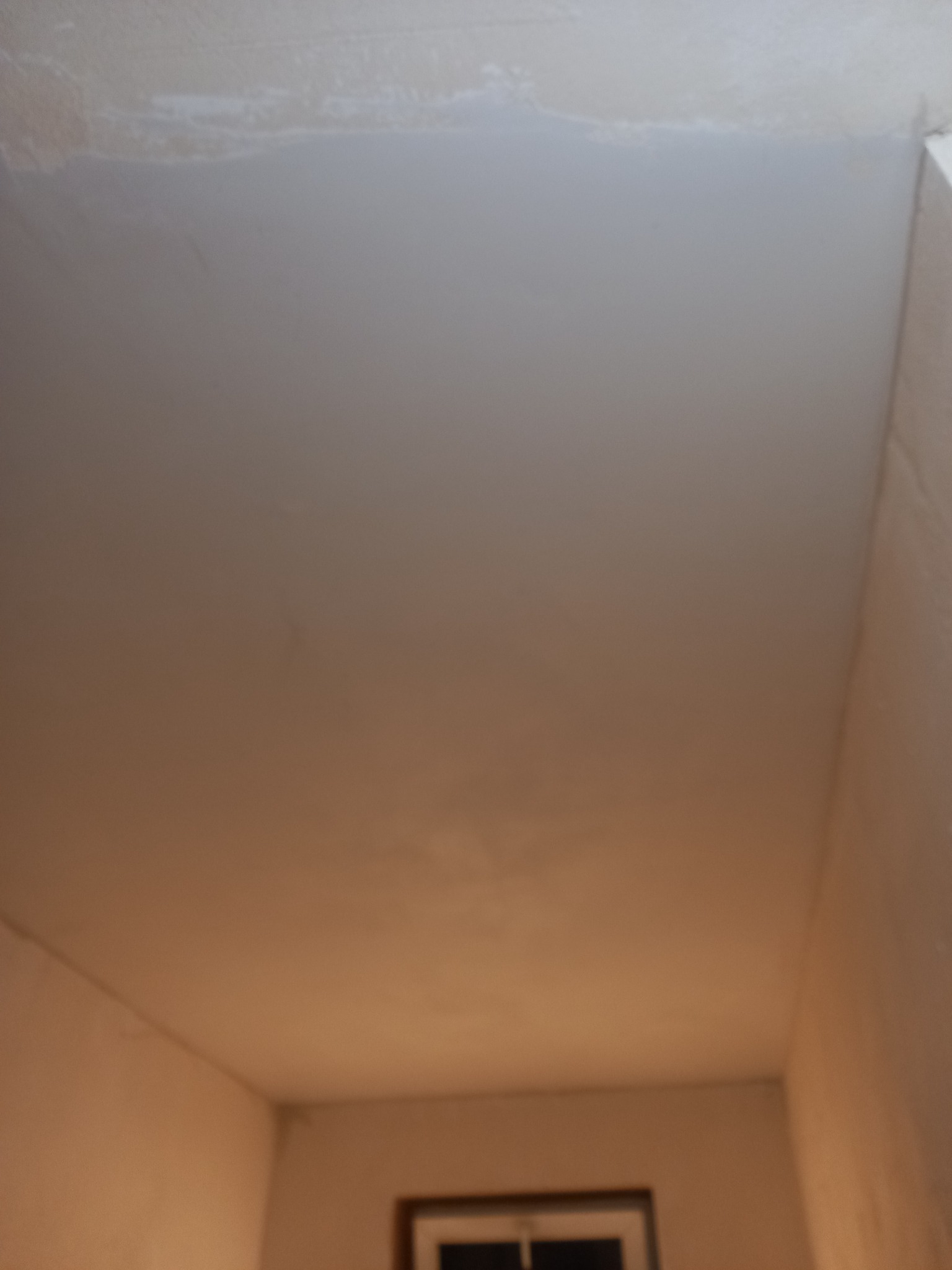 Surowy sufit po wstępnym etapie wyrównywania, widoczne ślady szpachli, przygotowanie do dalszych prac wykończeniowych.