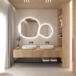 Paulina Teodorczyk - Architektura Wnętrz - Nowoczesna łazienka z podwójną umywalką, oświetlonym lustrem o organicznym kształcie i drewnianymi akcentami. Minimalistyczny design z subtelnym oświetleniem sufitowym.