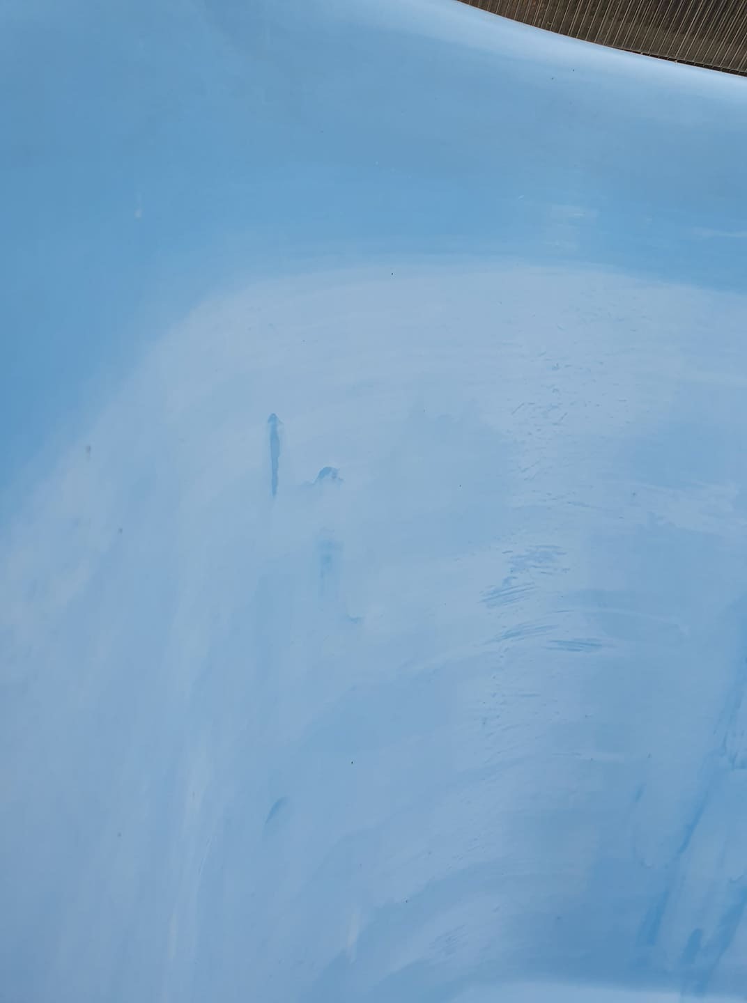 Błękitna, gładka powierzchnia przypominająca dno zbiornika wodnego we Wrocławiu, widoczne delikatne smugi i drobne zanieczyszczenia.