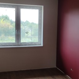 Well-bud - Pokój po remoncie z panelami podłogowymi w odcieniach brązu, pomalowaną na burgundowo jedną ścianą i widokiem za oknem na zieleń, z wystającym kablem ze sufitu.