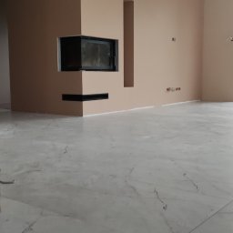 Well-bud - Minimalistyczny salon z wykończonym kominkiem w zabudowie, beżowe ściany i marmurowa podłoga z delikatnym wzorem żyłkowania.