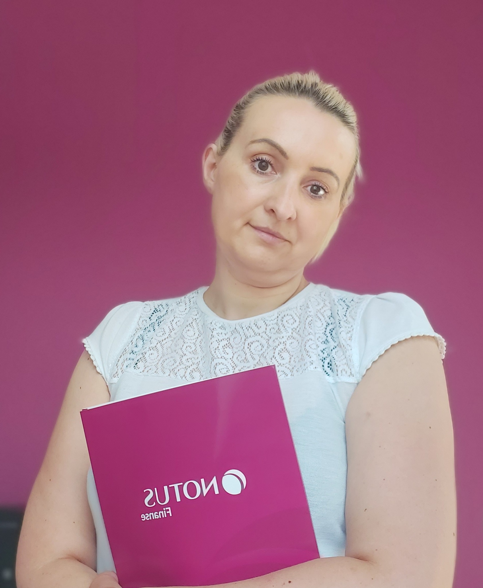 Portret kobiety trzymającej fioletowy folder z odwróconym logo firmy finansowej na tle fuksjowej ściany.