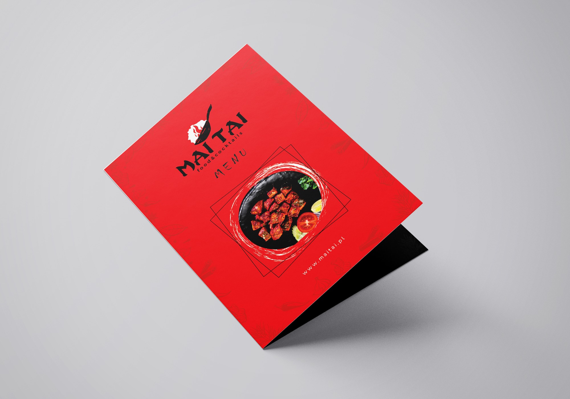 Czerwona ulotka menu restauracji MaiTai z daniem i logo, leżąca na szarym tle pod kątem.